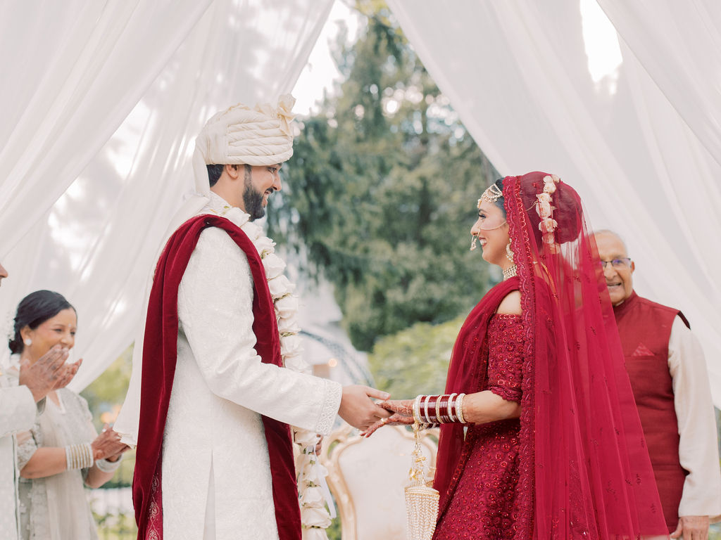 South Asian wedding ceremony planned by Madison Elyse Events — bride and groom exchanging vows beneath a white draped mandap